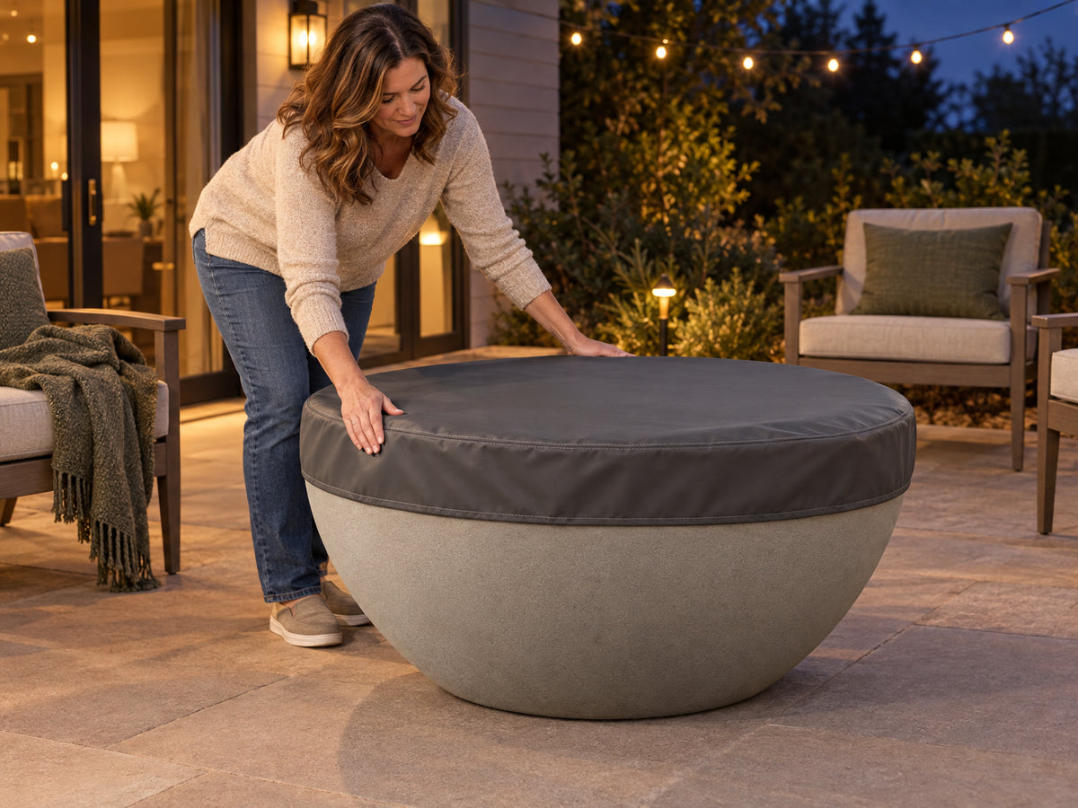 Round Concrete Fire Pit Designed, a woman smoothing a fitted vinyl cover down over the fire pit, snapping it into place
